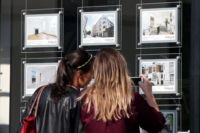 <p>A couple look at homes advertised in an estate agent’s window</p>