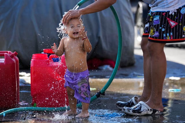 <p>A man pours water on his daughter on a hot day in Manila, Philippines</p>