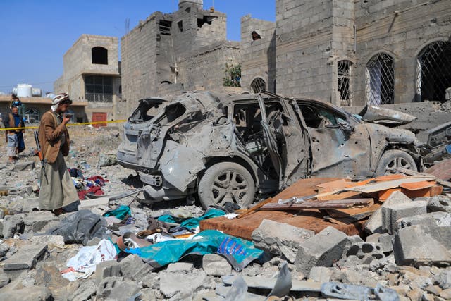 <p>File. An armed man speaks on his mobile phone as he checks the wreckage of a car at the site of a reported US airstrike in Sanaa, Yemen, on 7 April 2025</p>