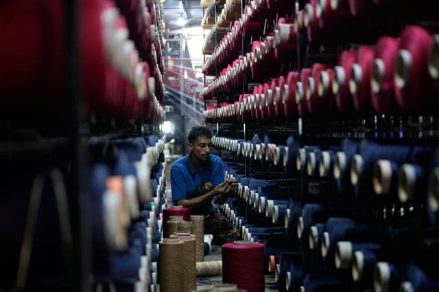 <p>An Indian worker checks thread reels on a carpet weaving machine in a factory on the outskirts of Jammu on 8 April 2025</p>